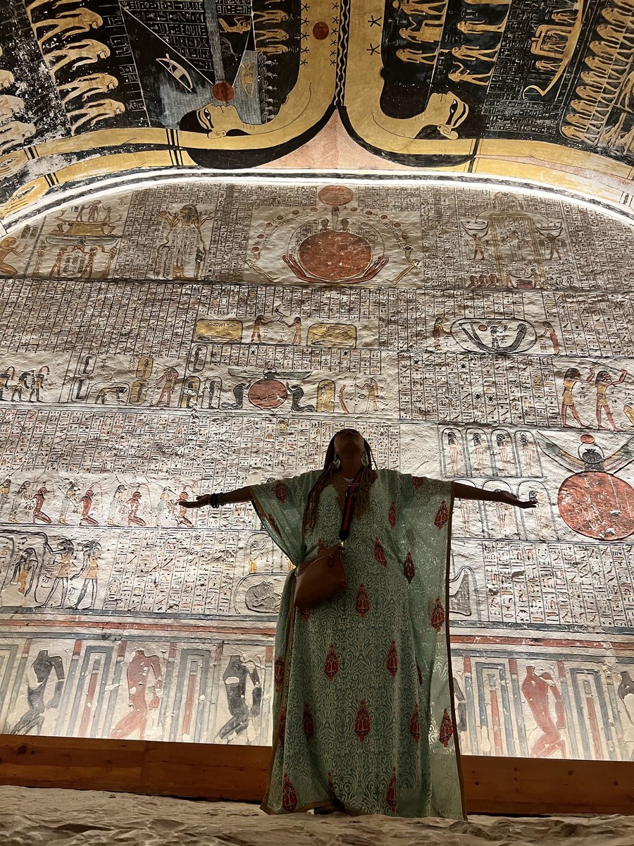 Sheharazaad standing with arms outstretched in an ancient Egyptian tomb, surrounded by hieroglyphics