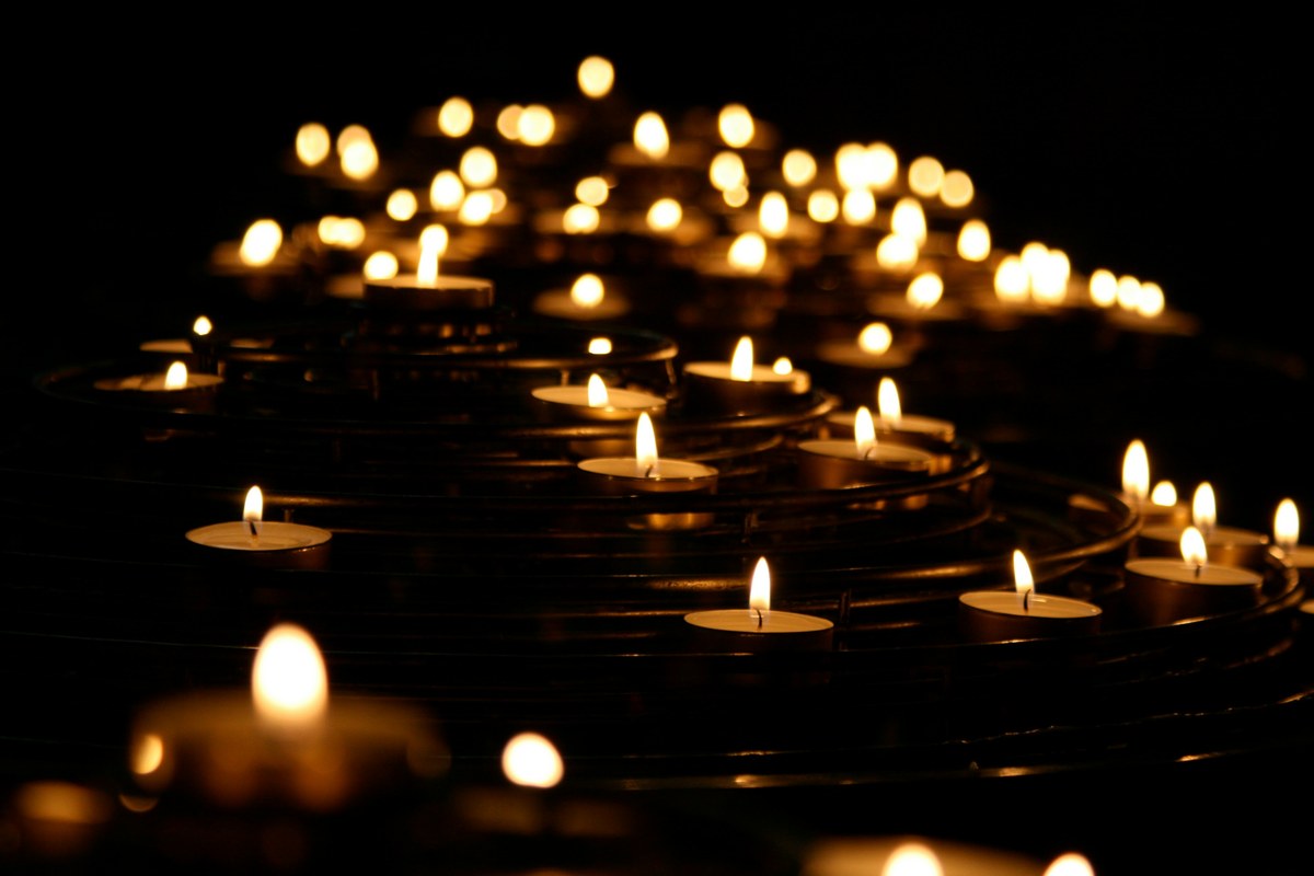 Many candles burning in the dark — holding grief that has no name