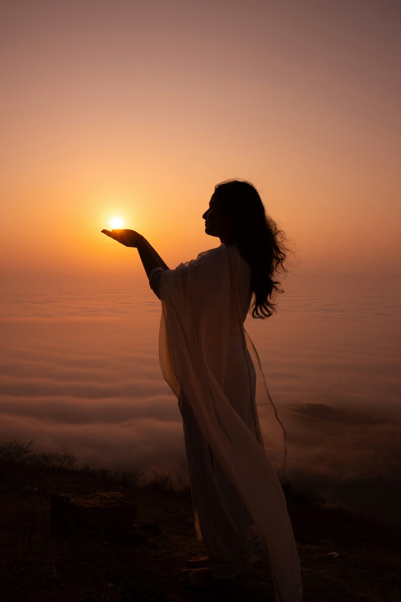 Woman holding the sun at sunrise — sovereignty and return to self
